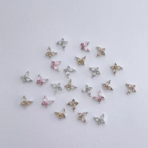 Assorted zircon butterfly nail charms in pink, gold, and silver laid on white surface