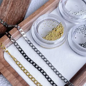 Mixed nail art chains and beads in gold, silver, and gunmetal laid in containers