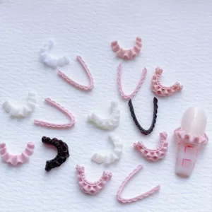 Mix of V-shaped and ruffled 3D lace nail charms on white background