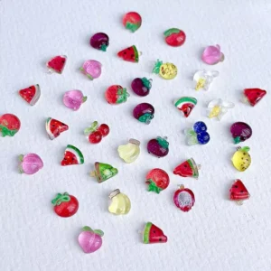 Mixed fruit nail charms in red, pink, and purple on paper