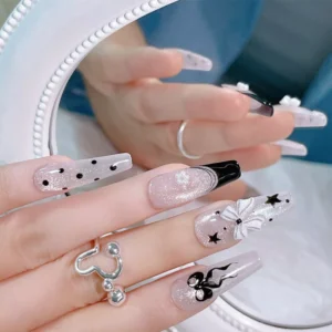 Hand model showing black and white bow nail charms on long glossy nails