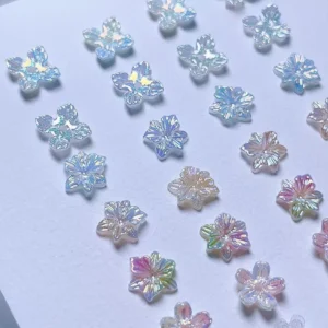 Variety of iridescent 3D flower nail decorations laid out by color
