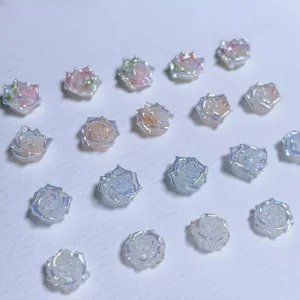 Assorted iridescent 3D rose nail charms in pink, peach, and blue tones