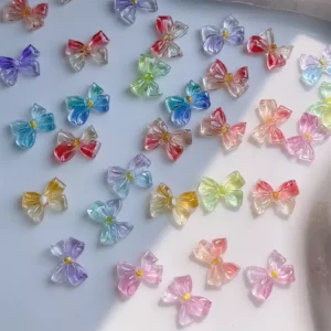 Multicolor glossy jelly bow nail charms laid out under direct light