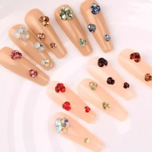 Nails decorated with various colored rhinestones, showcasing red, blue, and pink hues for a stunning effect.