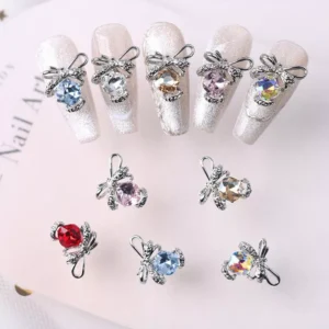 Close-up of crystal bow nail charms applied on shimmering silver nails