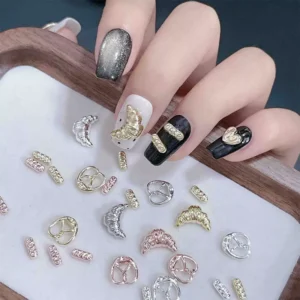 Overhead shot of metal nail charms in gold and silver with hand showcasing designs