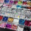 Multicolor nail glitter sequins in heart and star shapes displayed in organizer box