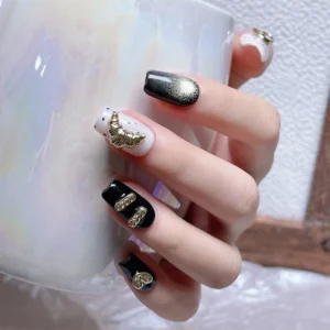 Hand model wearing metallic crescent and bead nail charms on matte and glossy nails