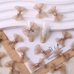 Beige mesh bow nail charms on warm nude-toned tips