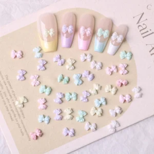Pastel mini bow nail charms arranged on beige card – soft 3D resin embellishments for nail art