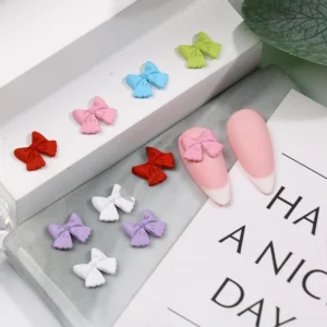 Close-up of pastel matte resin bow nail decorations on white tray