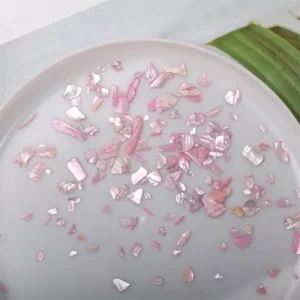 Close-up of iridescent pink nail flakes in scattered shapes