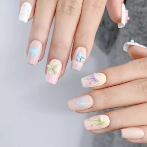 Bright pastel manicure with bow nail decorations in rainbow tones