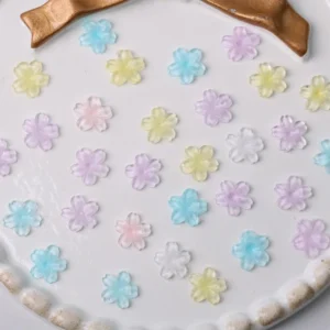 Pastel flower nail embellishments in assorted resin colors on white plate