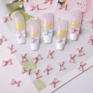 Pink glossy bow nail decorations with diamond accents on styled nail tips