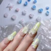 Resin rose nail charms with iridescent finish and 3D floral details on hand display