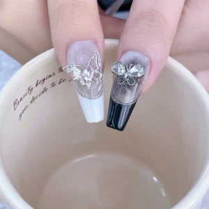 Model fingers with long nails featuring butterfly nail charms and ombré designs