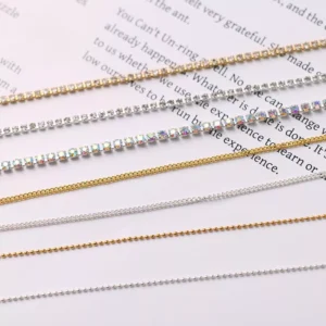 Close-up of nail chains in rhinestone, gold, and silver styles on white background