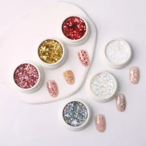 Flat lay of red and gold heart glitter jars with peach manicure examples