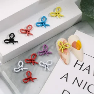 Rope-style bow nail charms in bright colors on decorative tray
