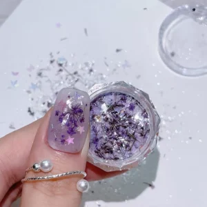 Purple floral shell glitter nail art shown on finger and jar