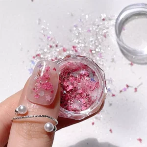 Pink shell glitter with dried flowers in nail art container and on thumbnail