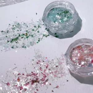 Shell Glitter Nail Charms scattered with green and pink dried flowers