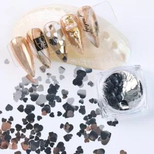 Silver heart nail sequins scattered on white surface with gold-accent nail designs