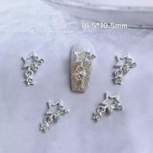 Silver star nail charms with hanging crystal details on soft white fabric background