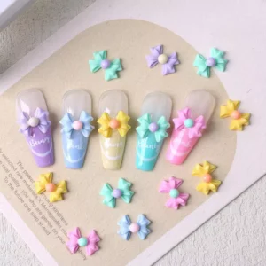 Pastel 3D bow nail charms styled with full tips on soft beige card