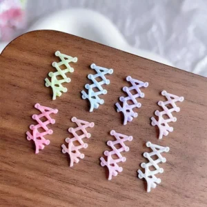 Pastel ballet ribbon nail charms arranged on wooden surface