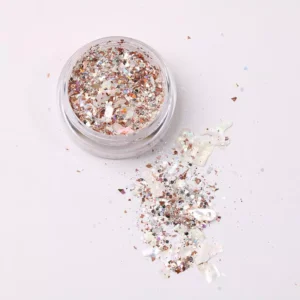 Rose-gold chunky flake glitter spilled beside open jar for nail decoration