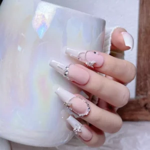 French-style pink nails decorated with zircon butterflies and mini pearls