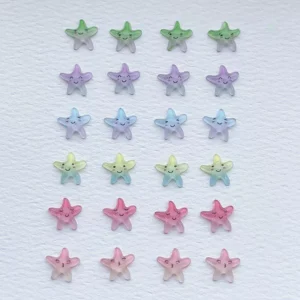 Green, purple, blue, and pink kawaii starfish nail charms arranged on white background