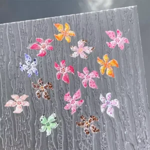 Transparent lily flower nail decals against a textured grey background
