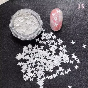 Jar of white butterfly nail glitter and translucent pink swatch nail decorated with butterflies