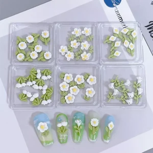 White floral nail charms with green leafy stems for garden-themed manicures
