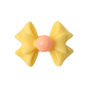Close-up of a yellow Glow Bow Nail Charm with pink center