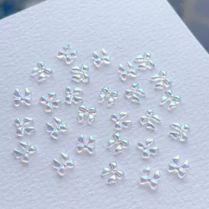 Iridescent clear mini bow nail charms displayed on white background
