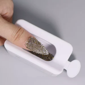 Close-up of finger dipped into Nail Powder Catcher Box filled with glitter