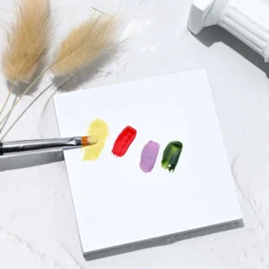 Gel brush blending four vibrant shades on disposable paper palette