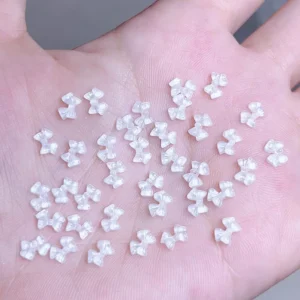 Transparent mini bow nail charms in hand for size reference